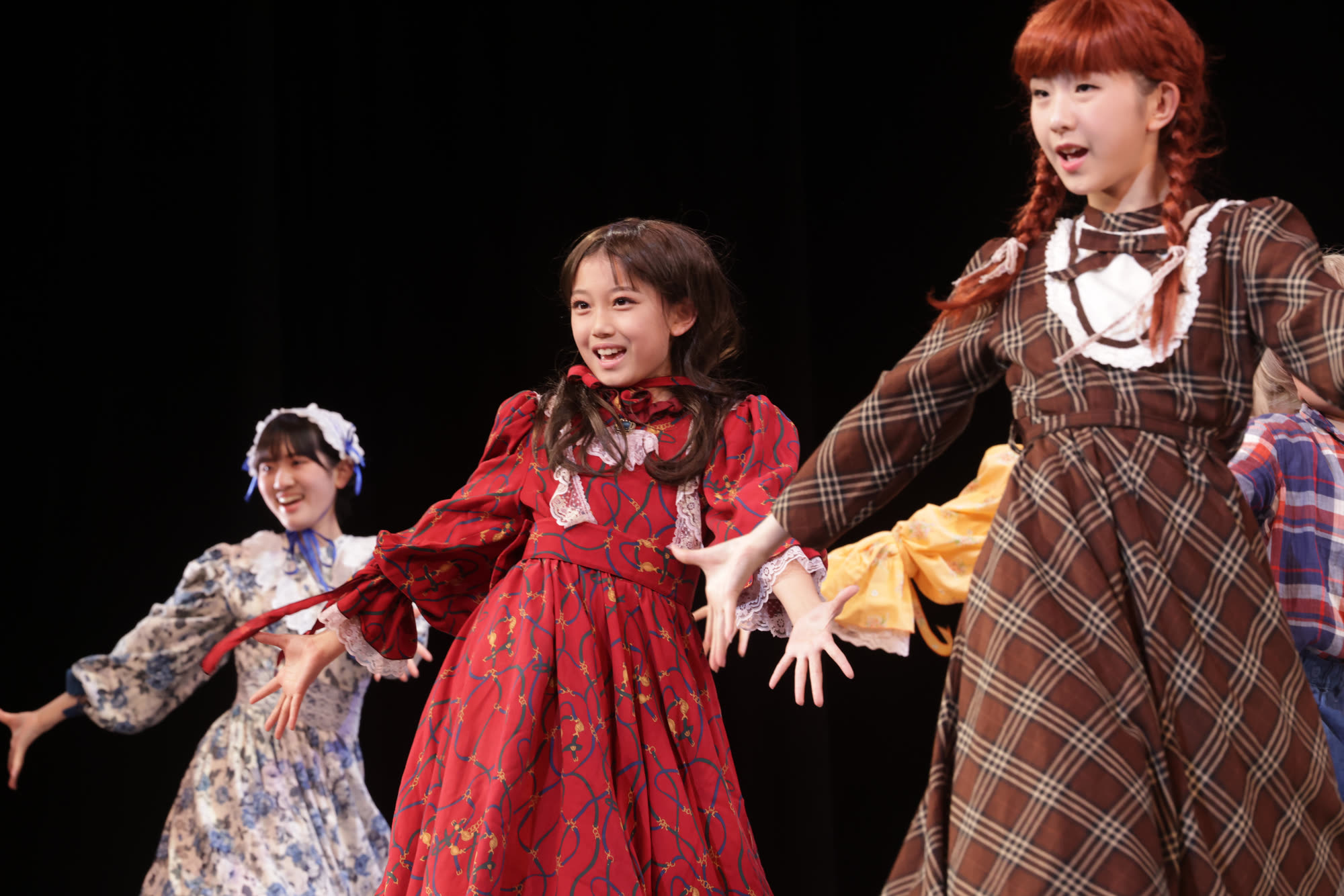 ドレスの少女たちが手を広げて歌う場面 ─ 音楽劇「赤毛のアン」本番の舞台より