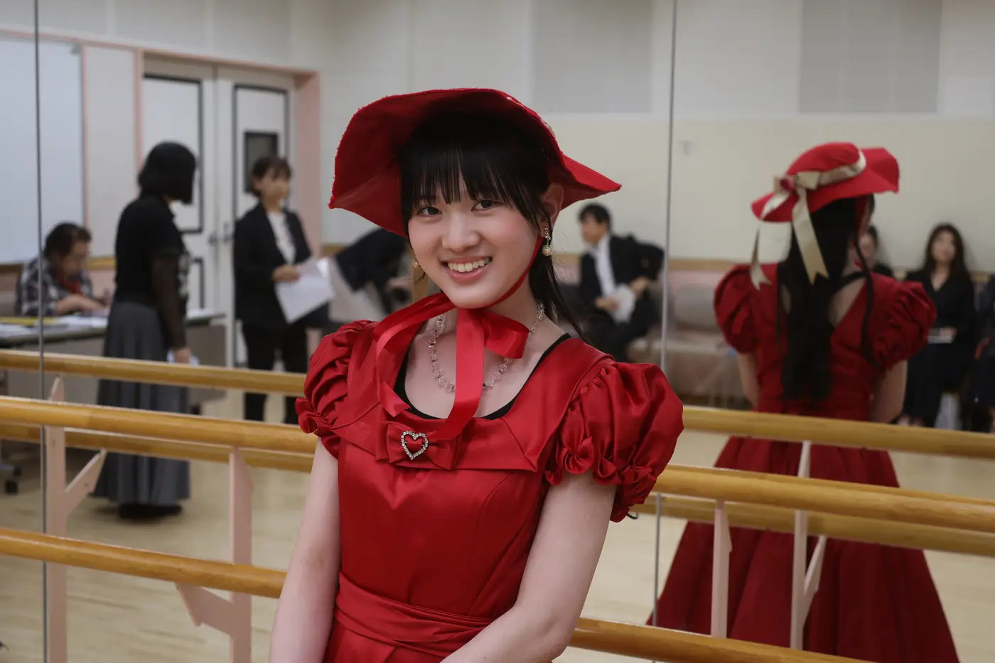 赤い帽子とドレスの衣裳で笑顔を見せる出演者